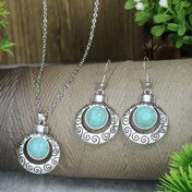 Resim Bir çift küpe ve bir kolyeden oluşan, metal yüzeyinde oyma tasarım ve kakma sentetik turkuaz bulunan, günlük kullanım veya partiler için uygun, kadınlar için tasarlanmış vintage bir takı seti. 