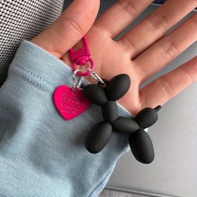 Resim Bir balon köpeği ile fuchsia ve siyah renkli, sevimli ve benzersiz bir çanta aksesuarı olan yaratıcı bir anahtarlık. 