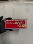 Resim HBSİ KIRMIZI RENK ÜZERİ HOLOGRAM RENK ZALIMIN KIZI YAZILI VANTUZLU CAM SÜSÜ 